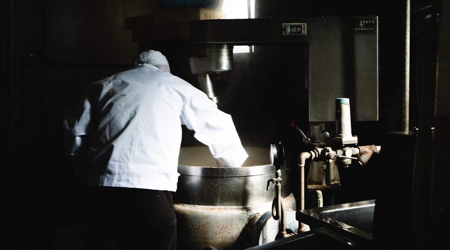 鍋の中のあんこを混ぜる職人の背中